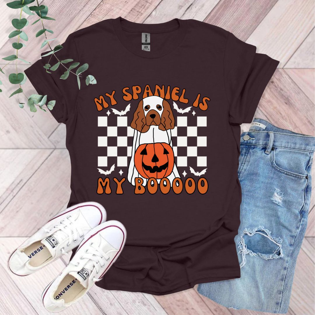 a brown and white dog wearing a pumpkin shirt
