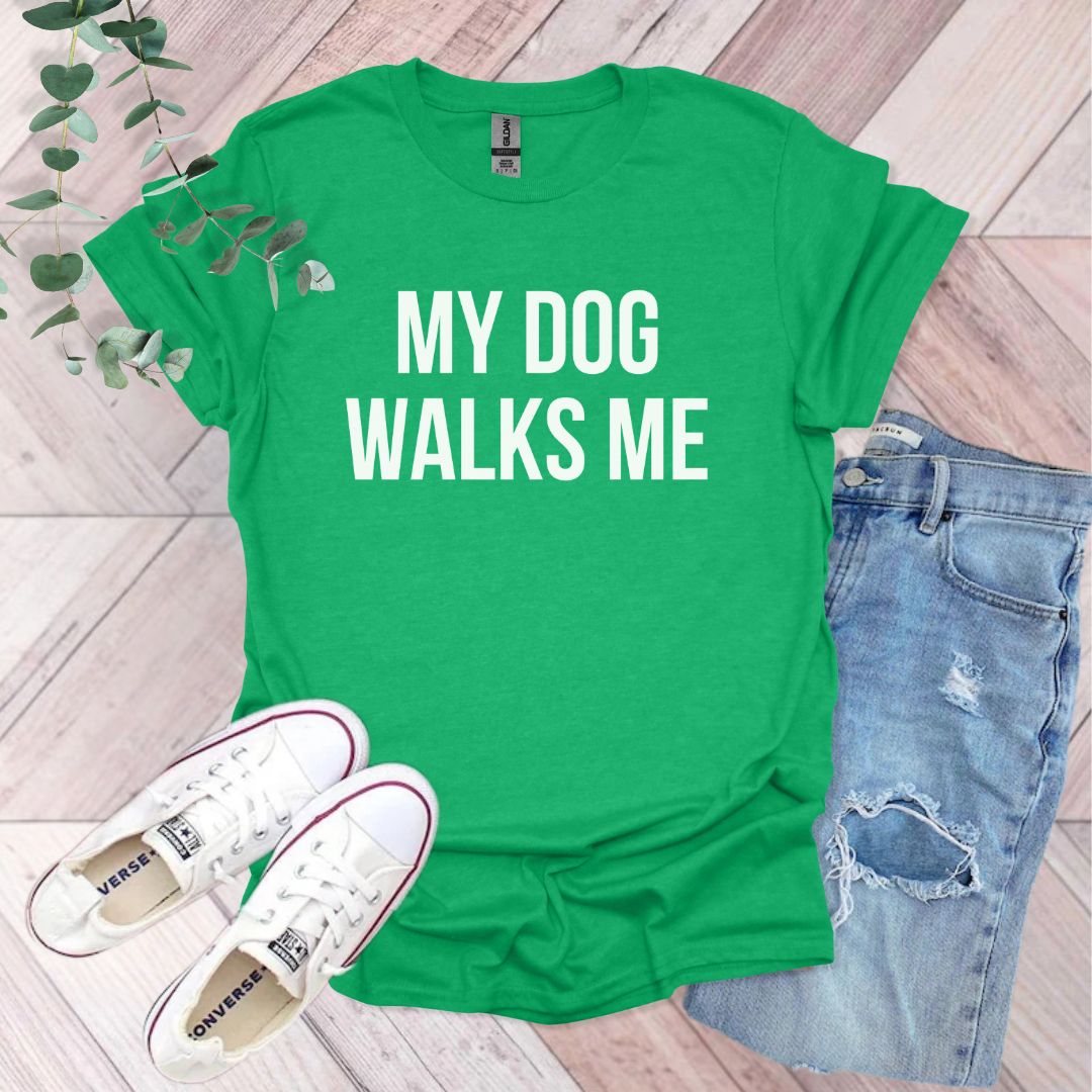 a green shirt that says, my dog walks me