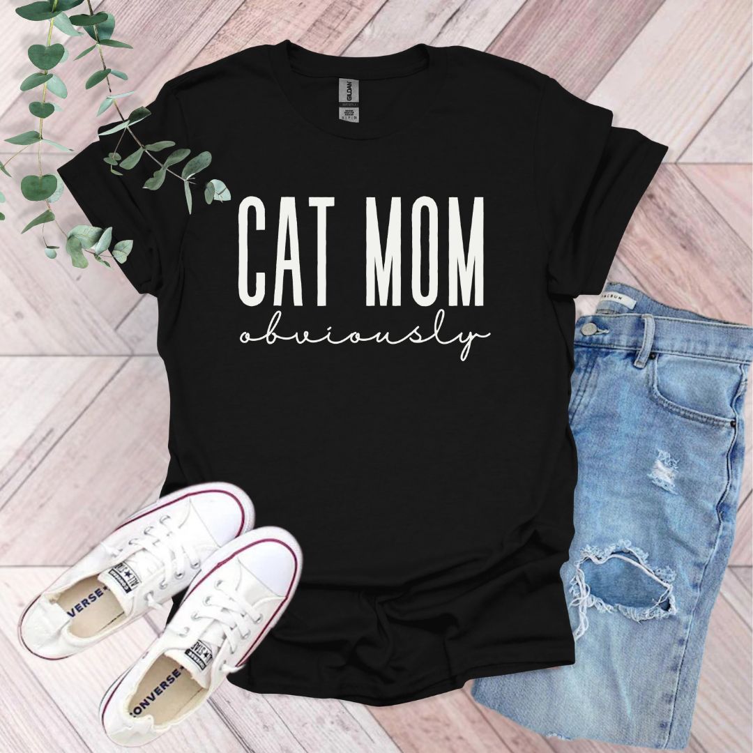 a t - shirt that says cat mom university next to a pair of jeans