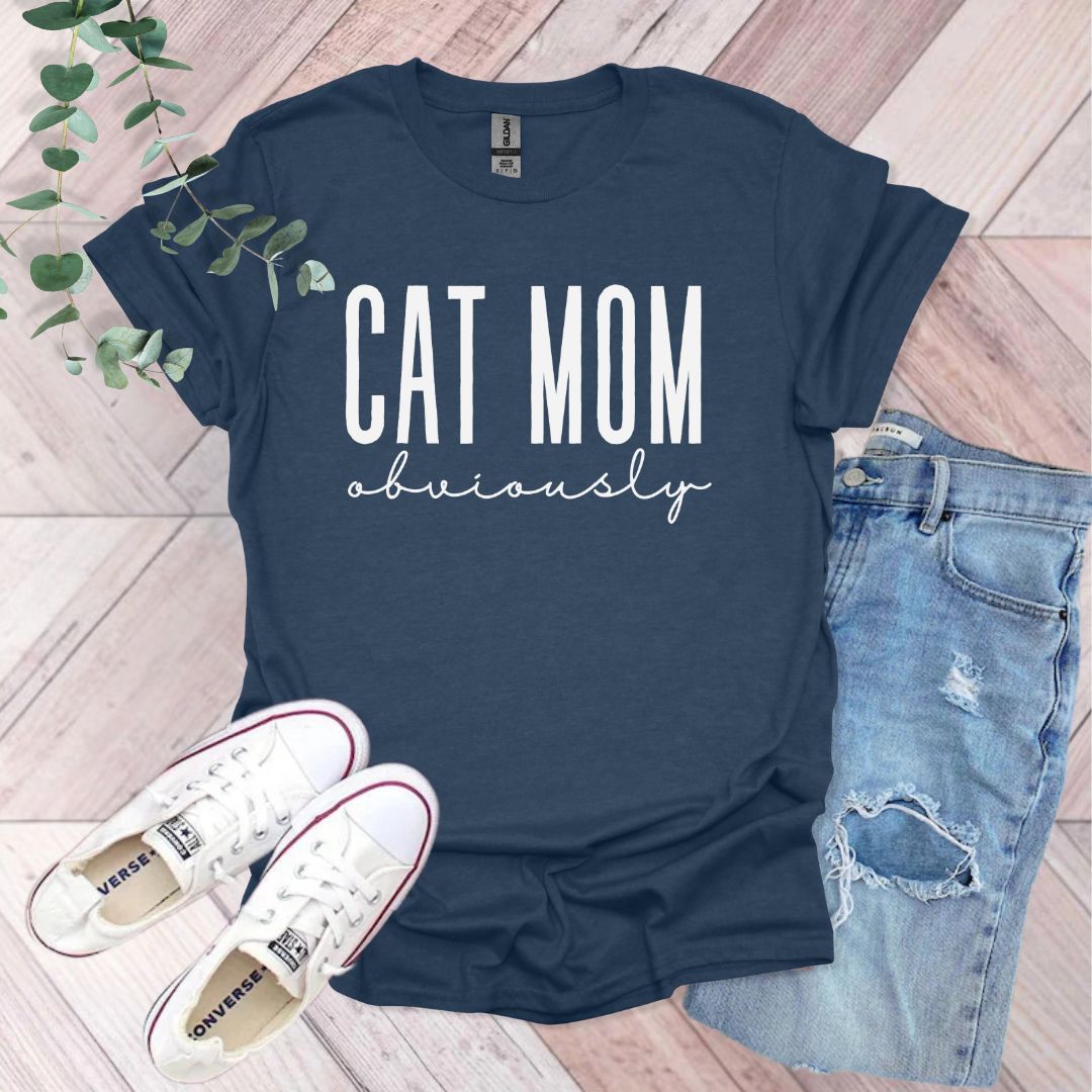 a t - shirt that says cat mom university next to a pair of jeans